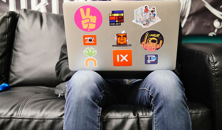Student working on laptop covered in stickers
