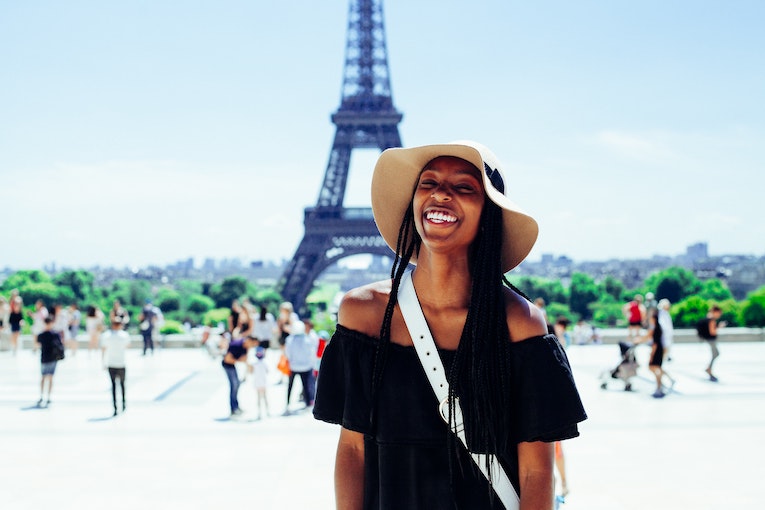 smiling person in focus with Eiffel Tower blurred in the background