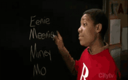 Boy pointing to options on a chalkboard, Eenie, meenie, miney, mo.