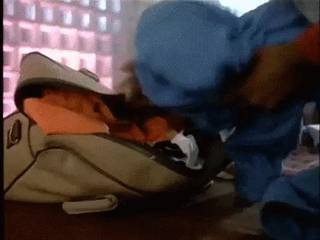 gif, man shoving clothes into bag with his foot