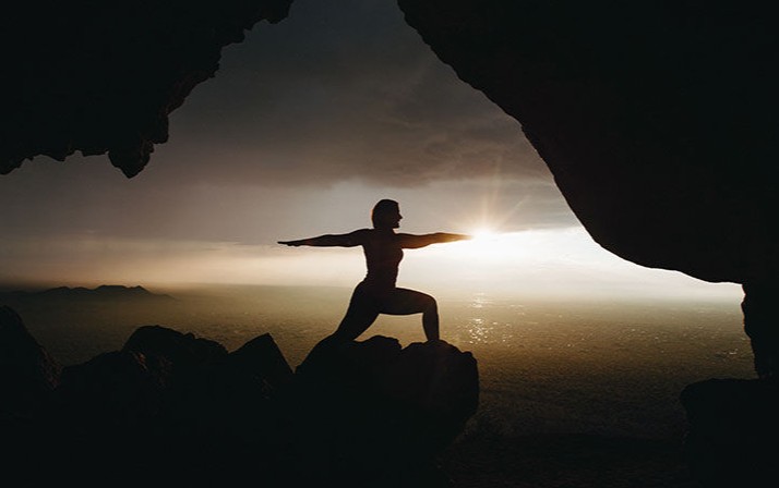 Woman doing yoga pose in front of sunrise