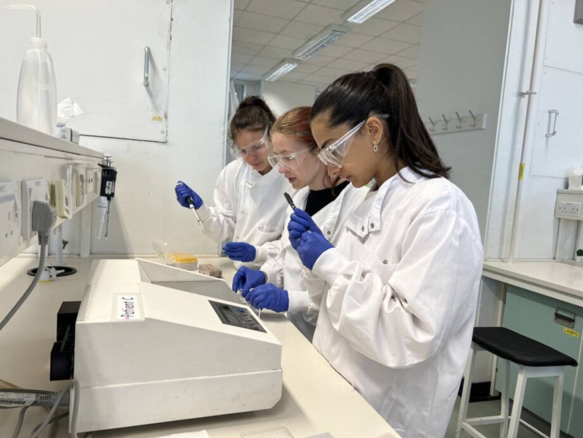 3 students using lab equipment in lab coats