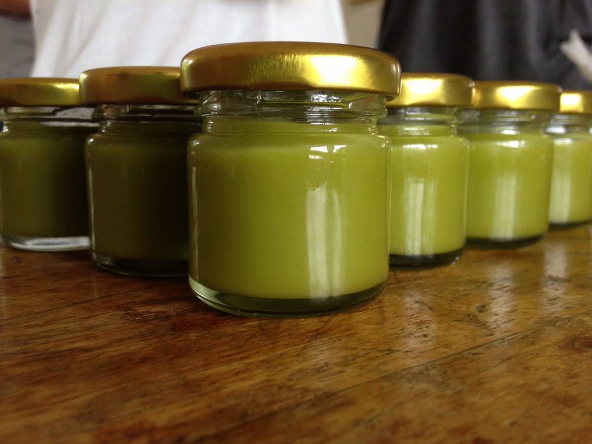 A close up of green salves in glass jars.