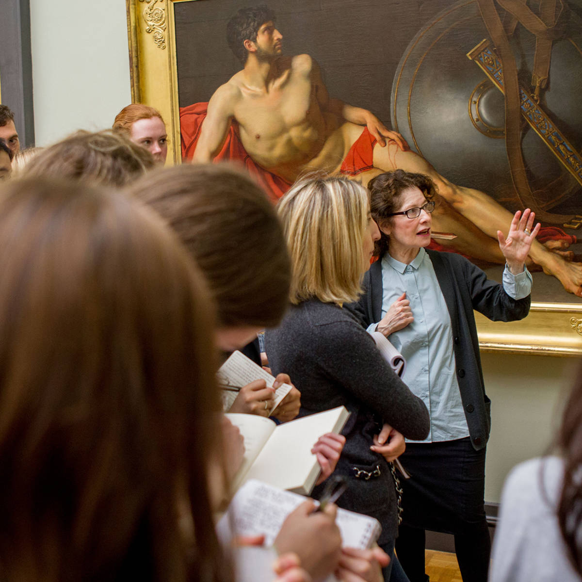 A faculty member explains a piece of art and students listen.
