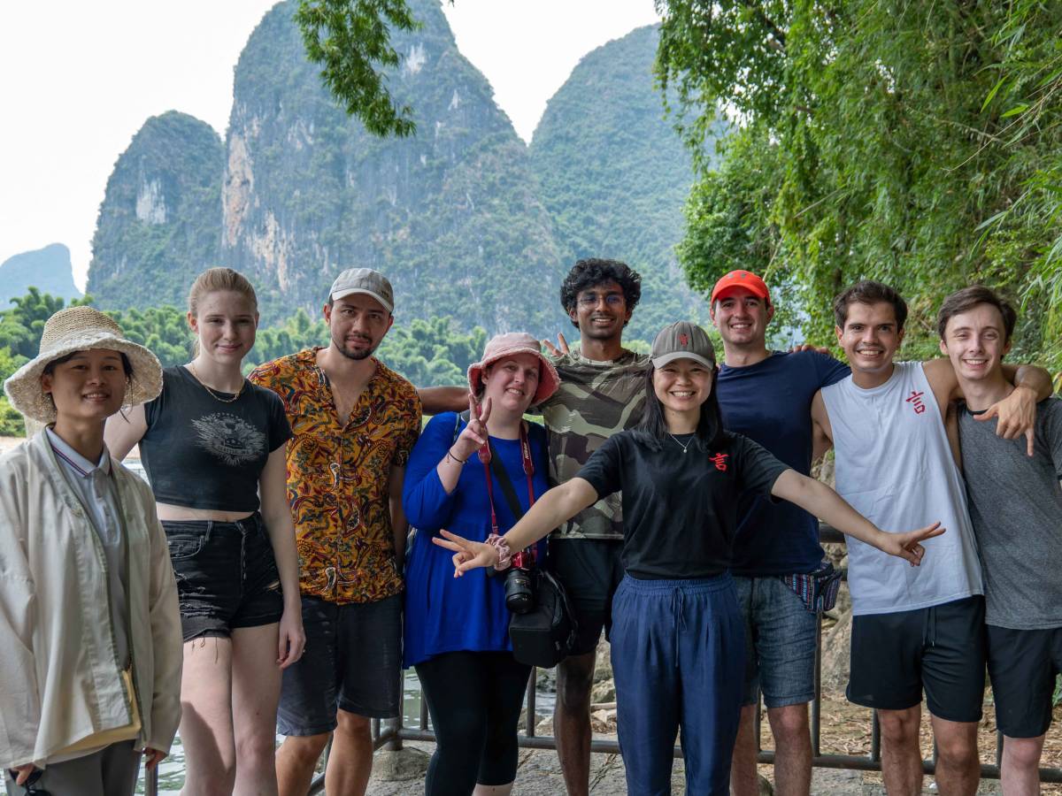 A group of CLI students and teachers pose together in front of the limestone peaks of Yangshuo along the Li River.