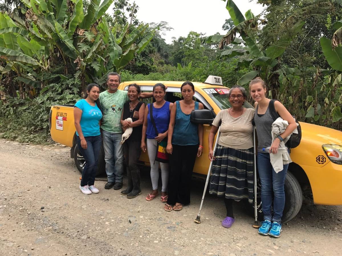 A group poses for a pic in front of taxi.