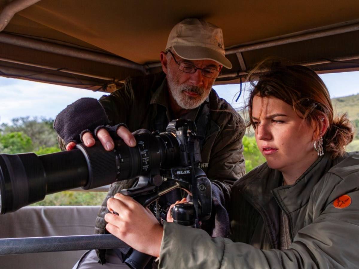 A guide helping a guest set up a telephoto camera lens on a South Africa Penda Photo Tour Safari