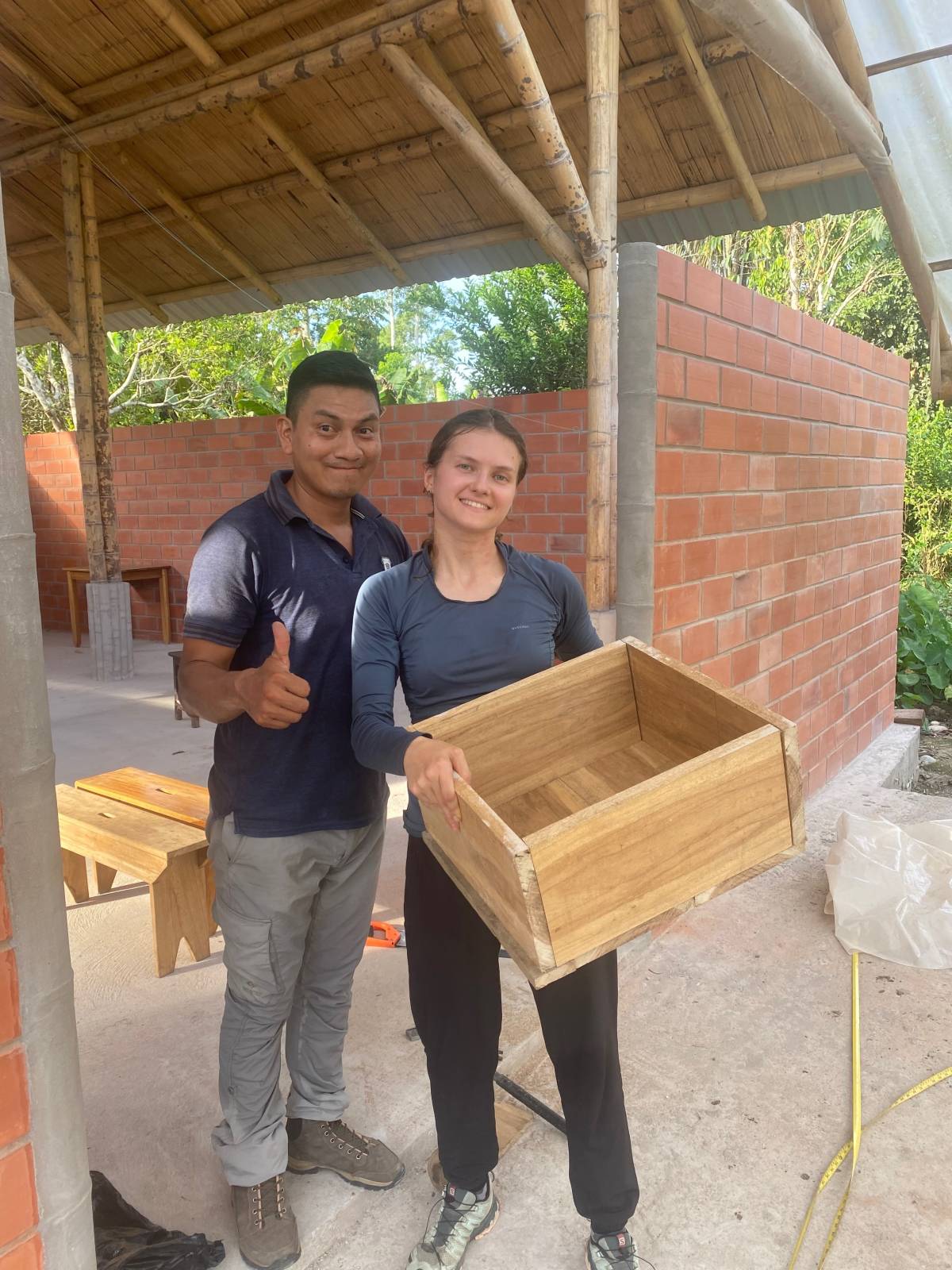 A man and woman smile, the woman holding a wooden box.