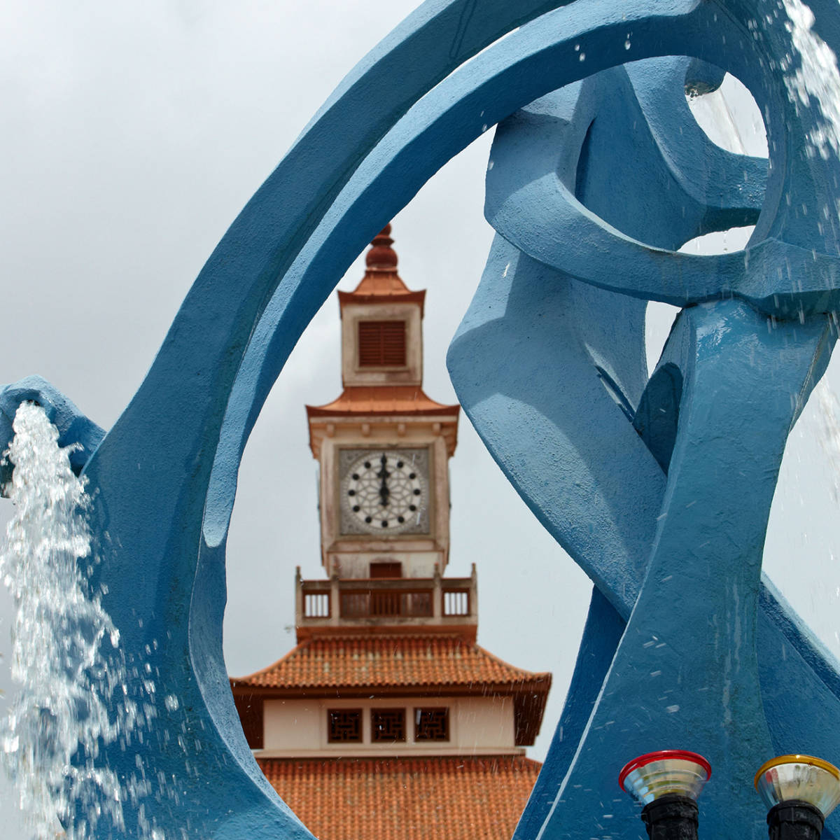 A shot of a University of Ghana-Legon clocktower through with an artistic fountain in the foreground.