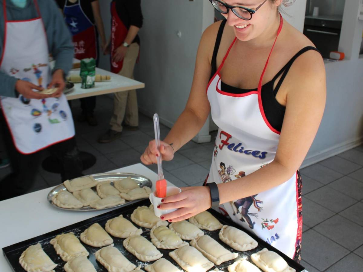 a student wearing an apron and preparing Chilean empanadas