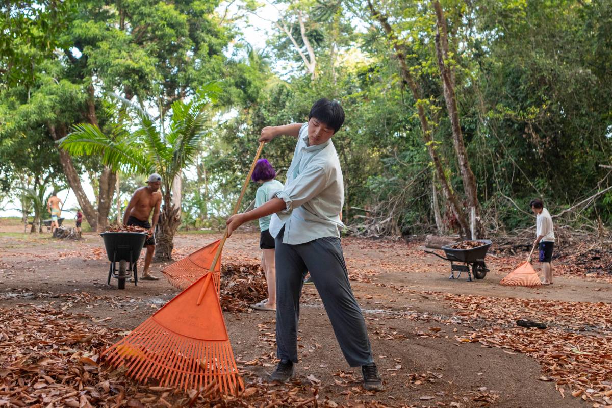 Boy rakes leaves with trail maintenance crews.