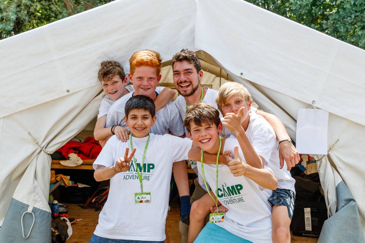 Children and camp learner smile in front of an activity tent
