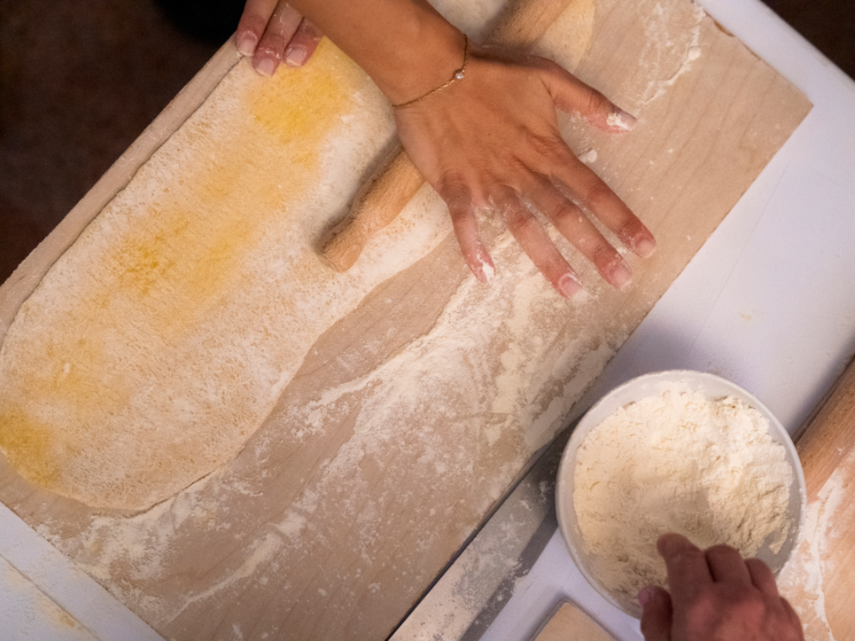 Close-up of hands rolling out fresh pasta dough during an Italian cooking class in Rome.