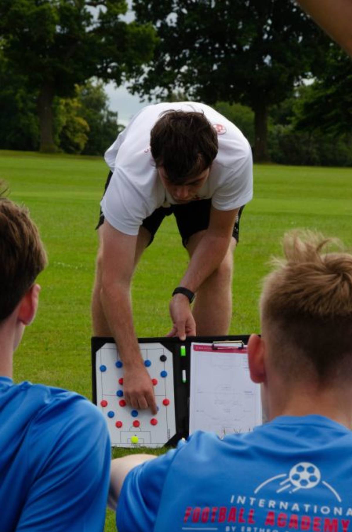 coach talking to players with a clip board