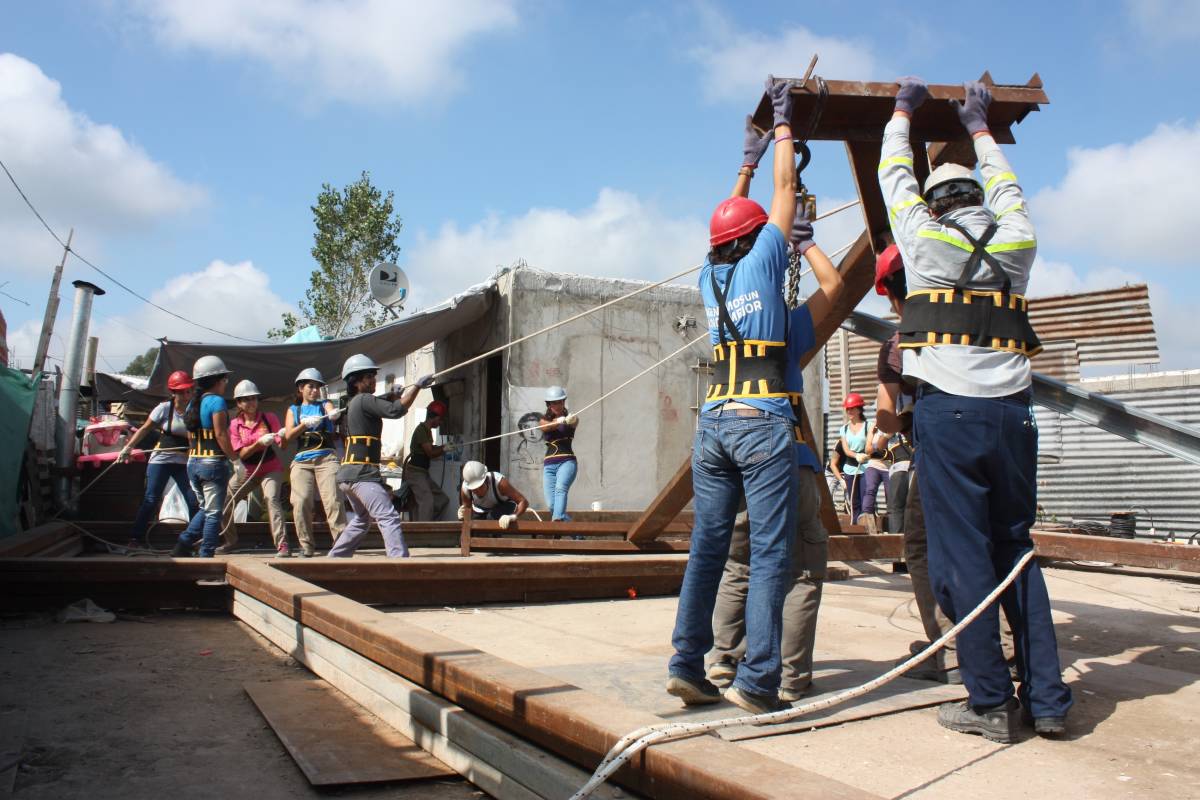 Engineering volunteers raising metal structure at community project