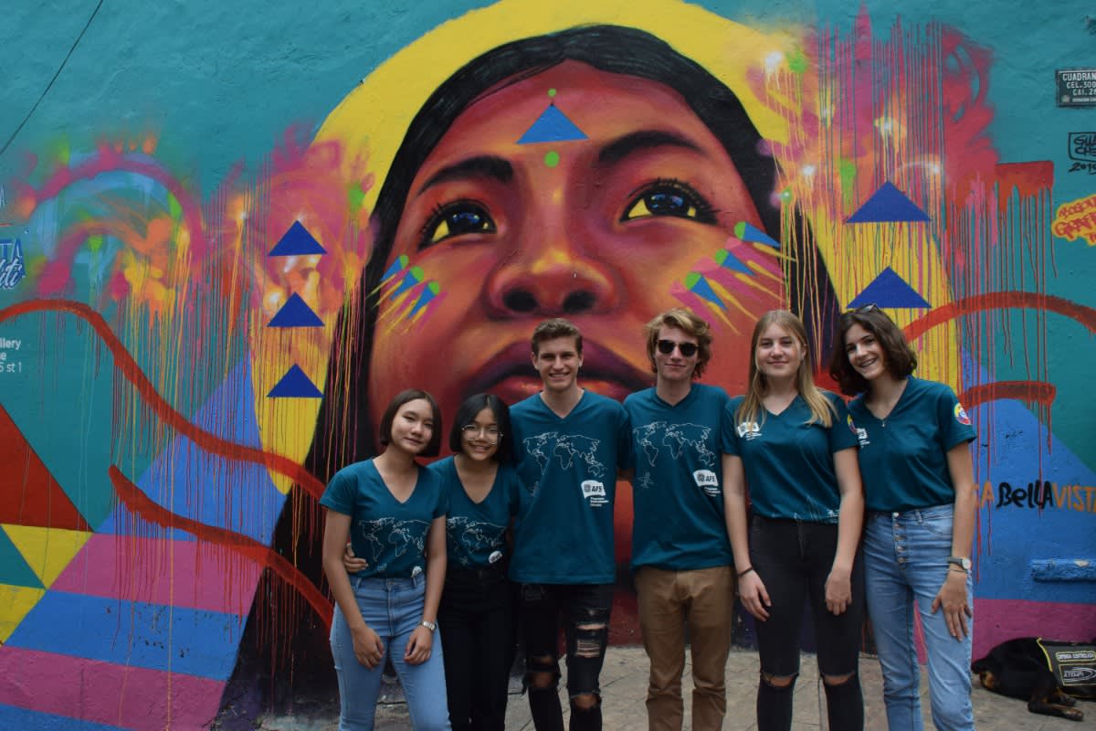 exchange students enjoying their time in Colombia while in front of a city mural