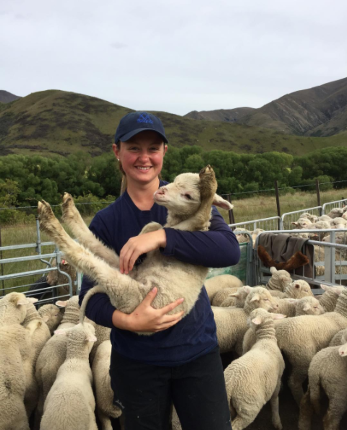 Farmstay girl holding a lamb with hills in the background