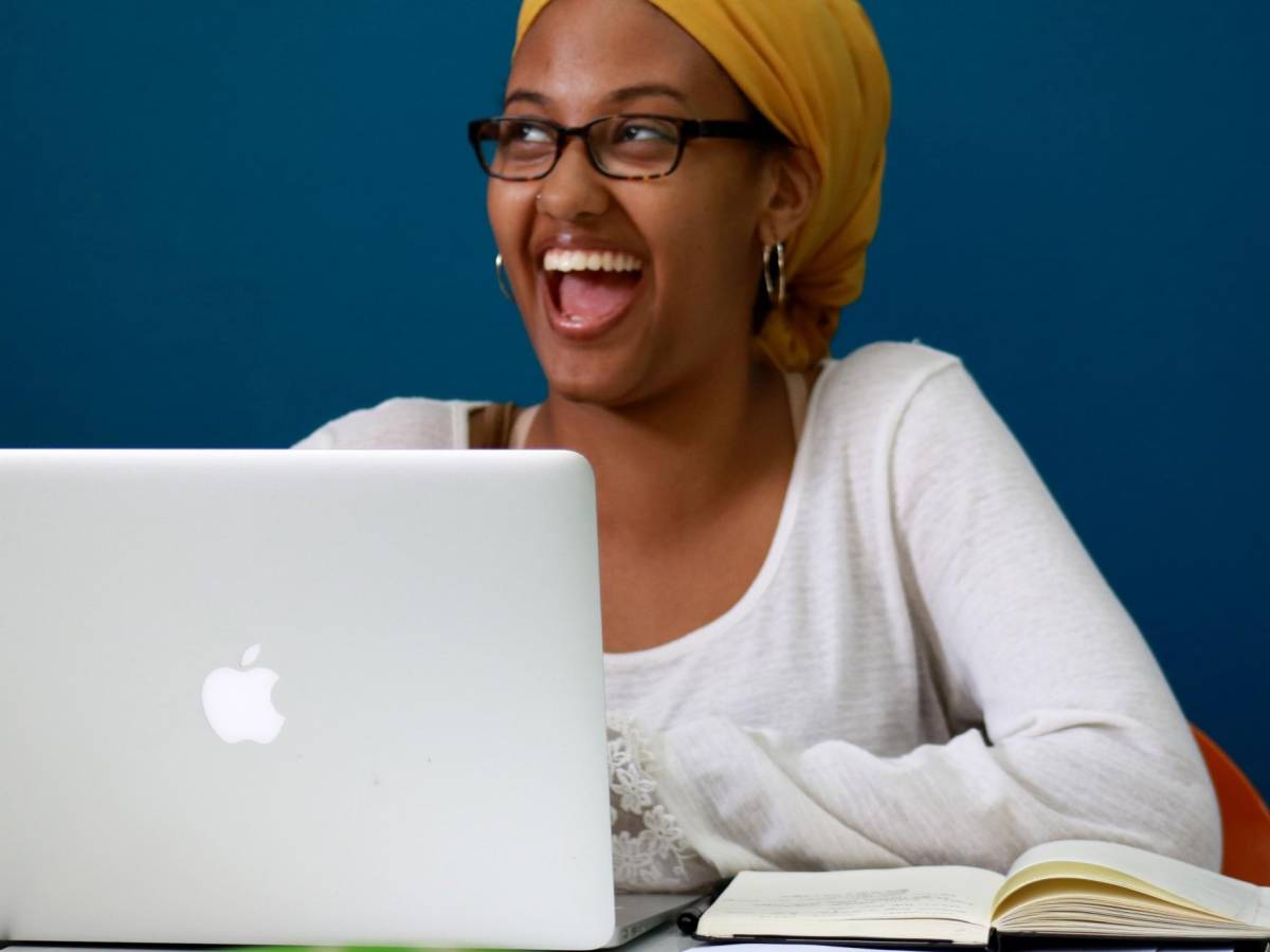 Female student laughing while using laptop in Rabat