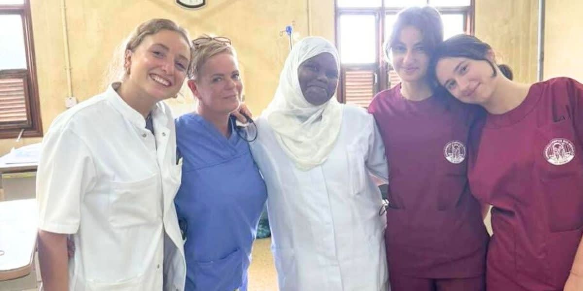 Five smiling women wearing scrubs.