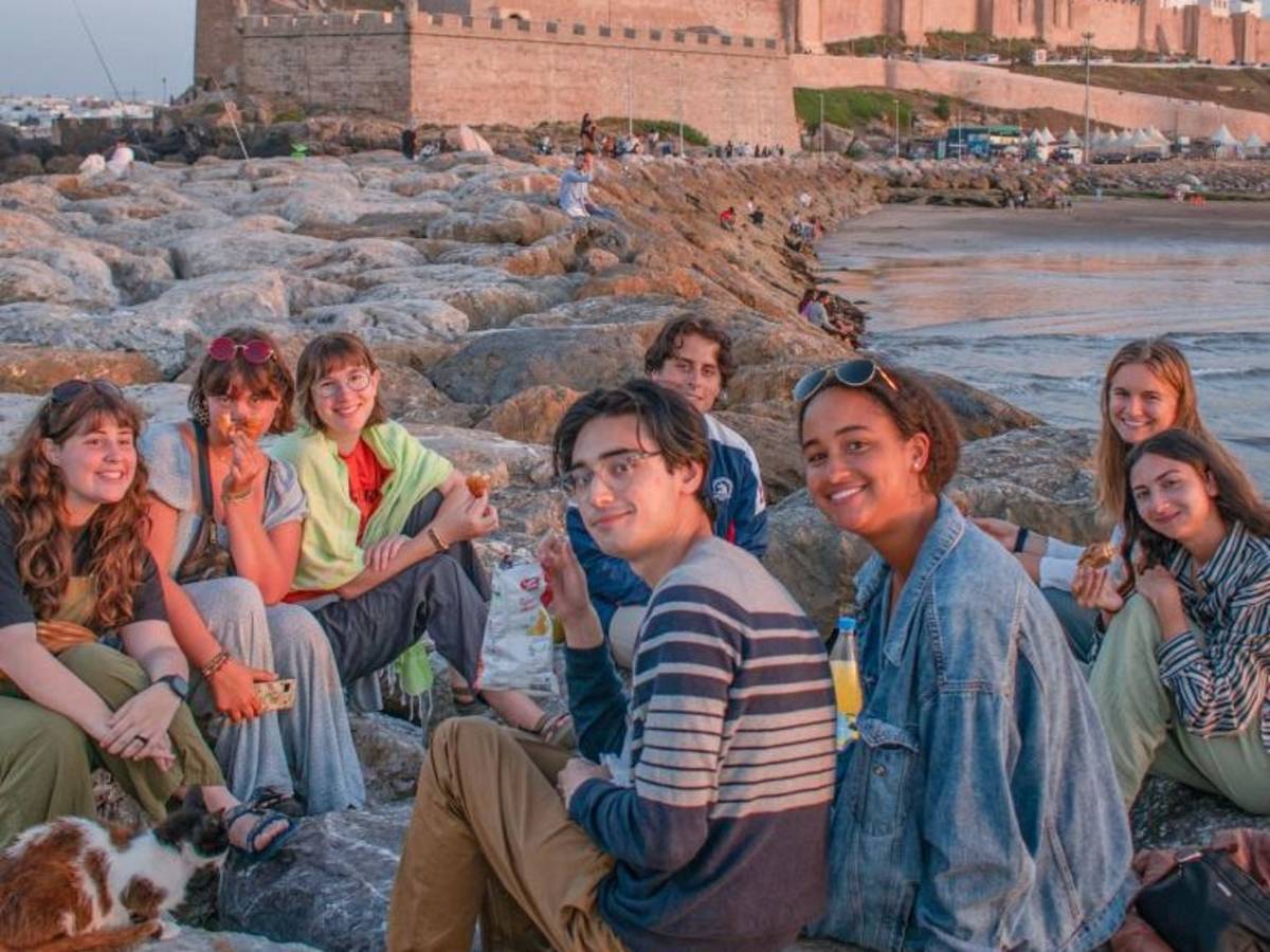 Group of Rabat study abroad students sitting and smiling next to waterway.