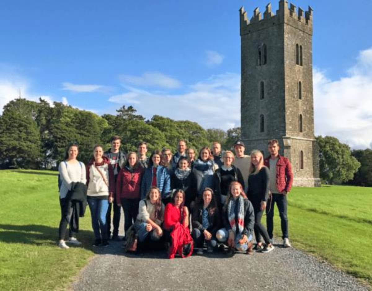 Students posed in front of a castle in the countryside