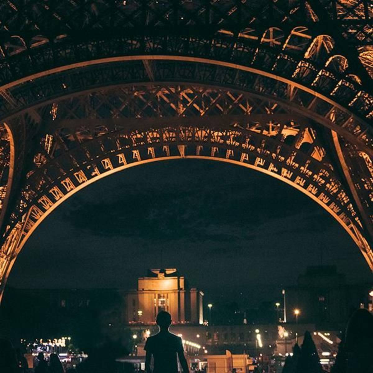 CEA Study Abroad Paris Student Under the Eiffel Tower at Night in Paris France