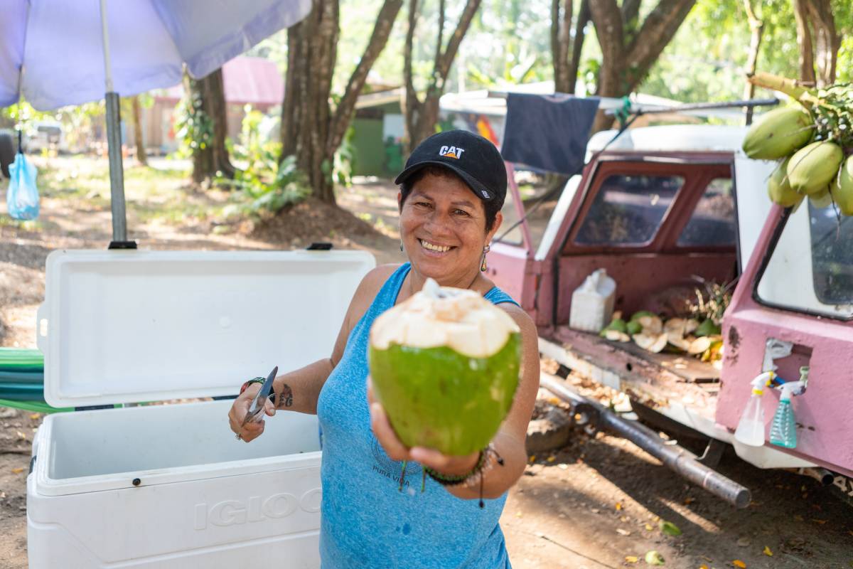 Smiling woman holds out fresh coconut