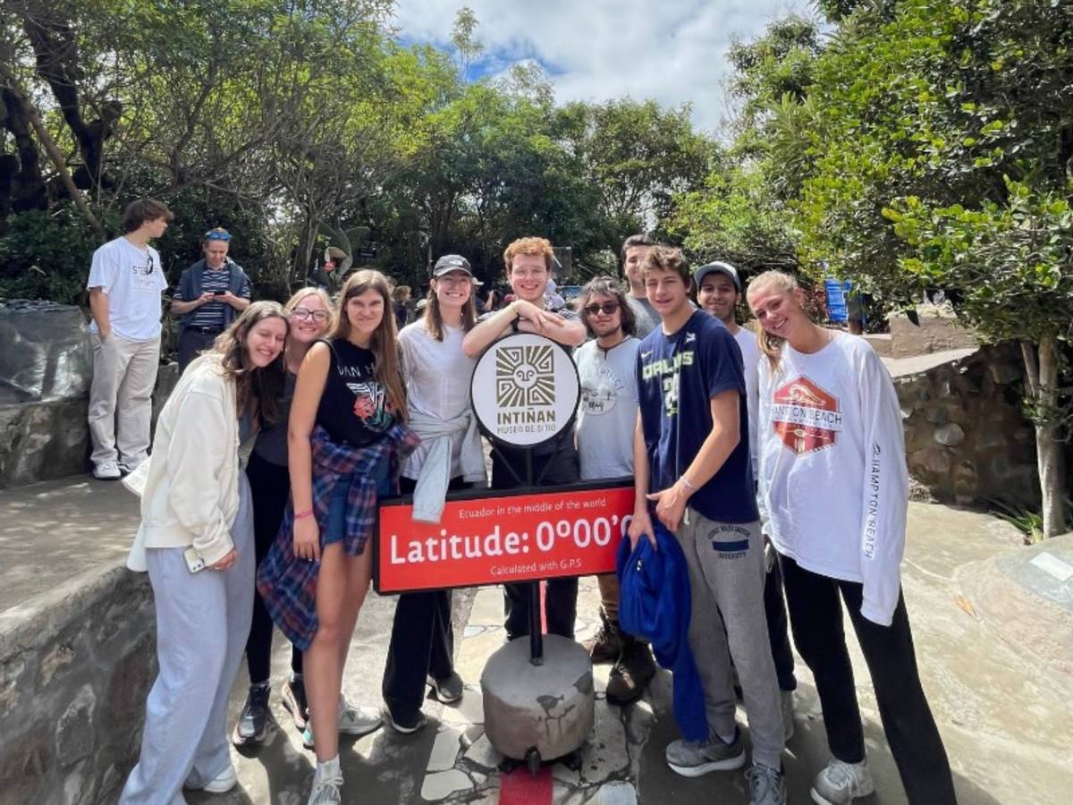 Student at the middle of the world Ecuador sign