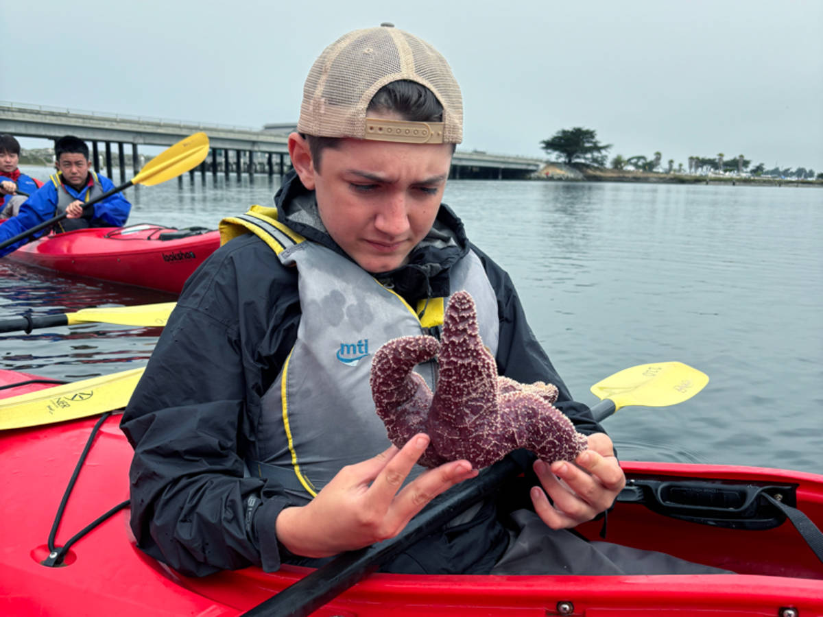 student holding a star fish in a kayak