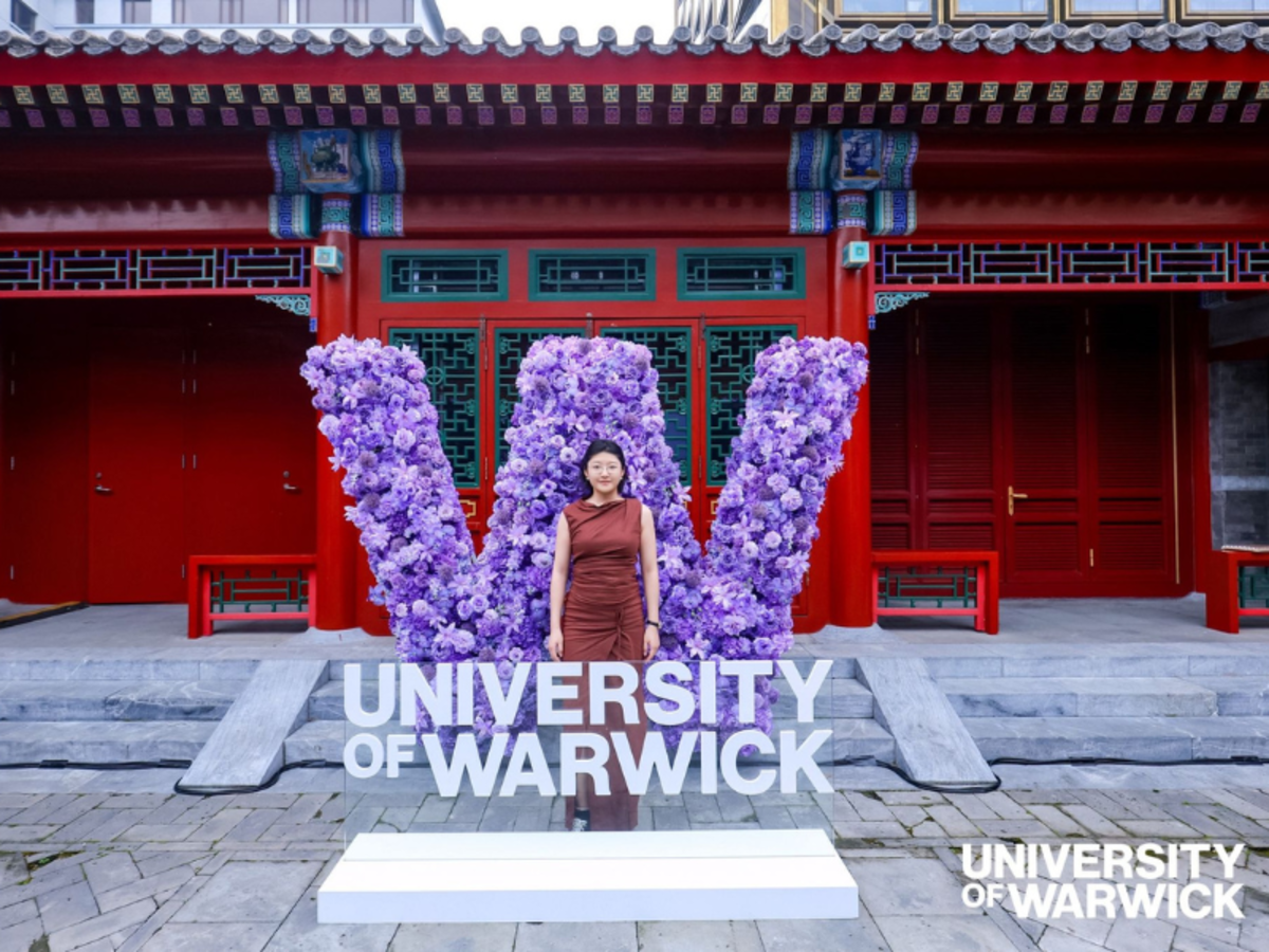 Student in front of a big W and University of Warwick sign