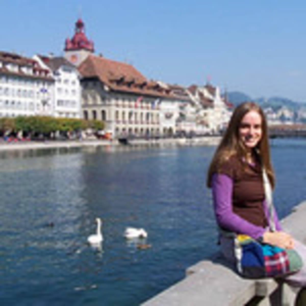 Student in front of canal with birds and houses in the background