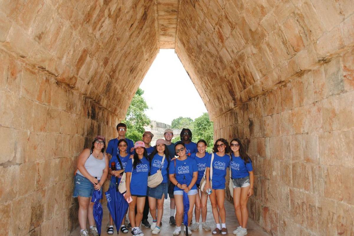 Student posing under Mayan arch