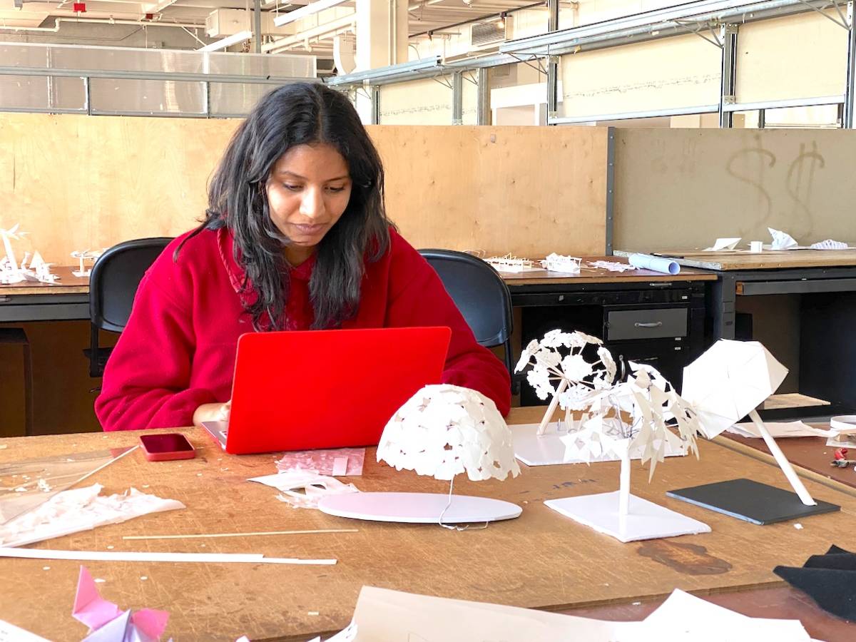 student working on computer with models in foreground