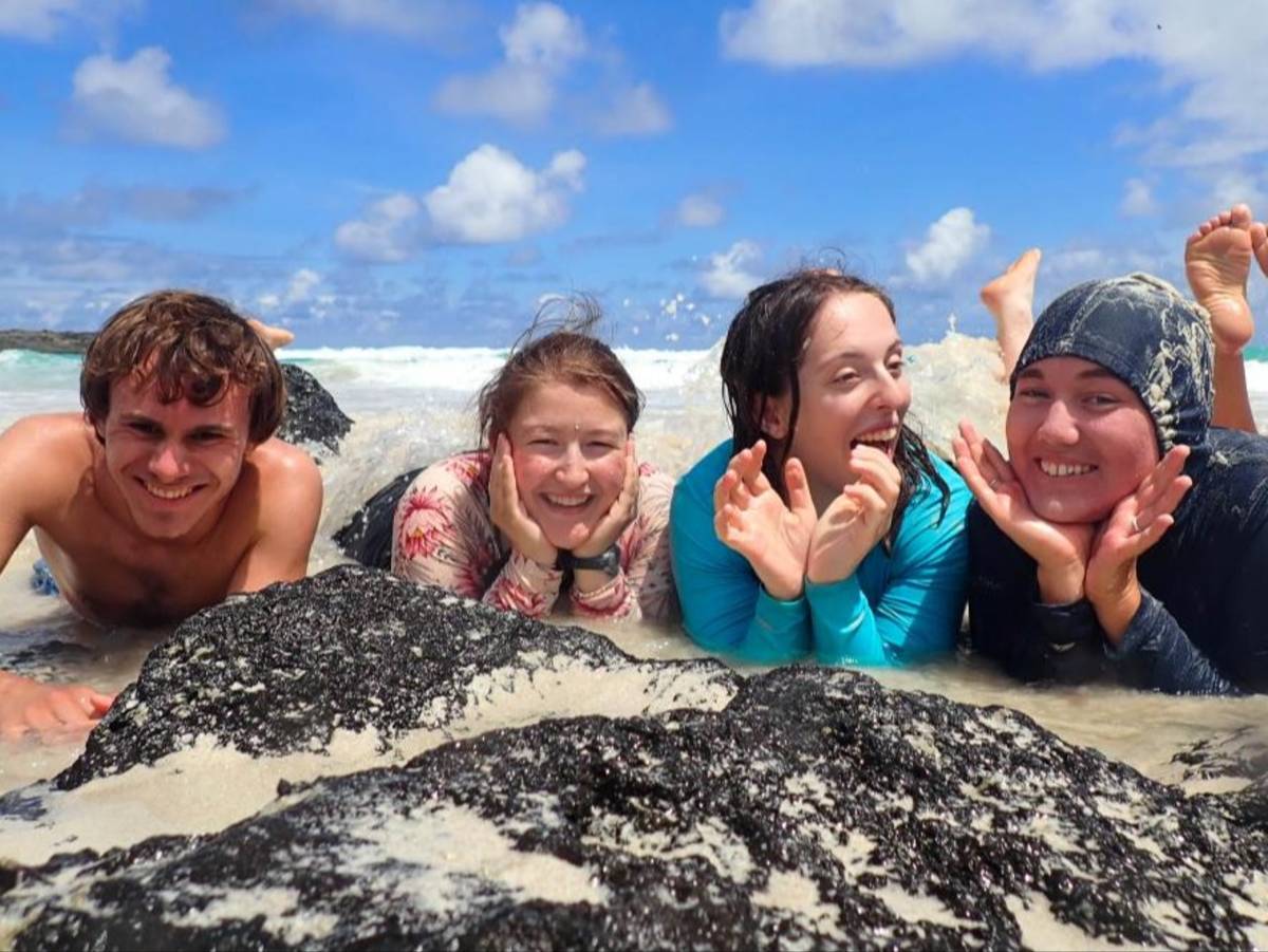 Students laugh on a beach in the Galapagos Islands.