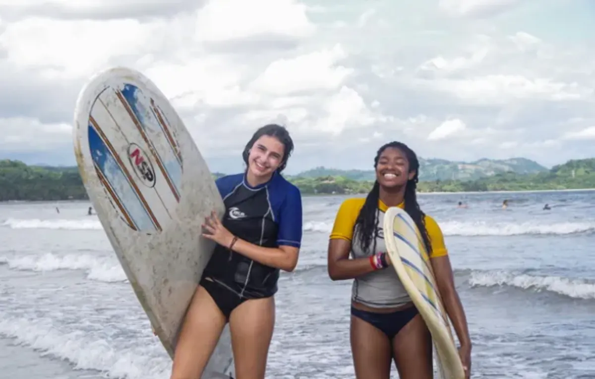 Students on beach holding surfboards