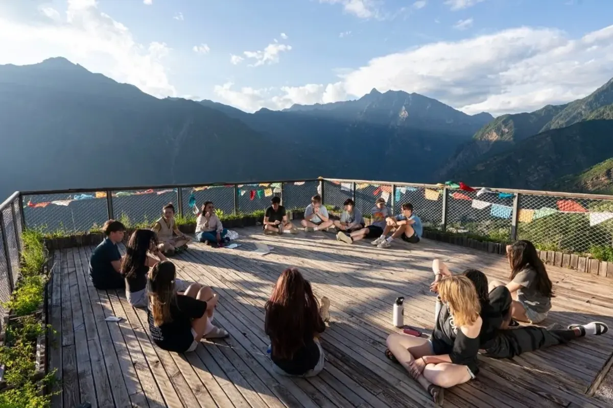 Students sit in a circle with mountain range in China in the background