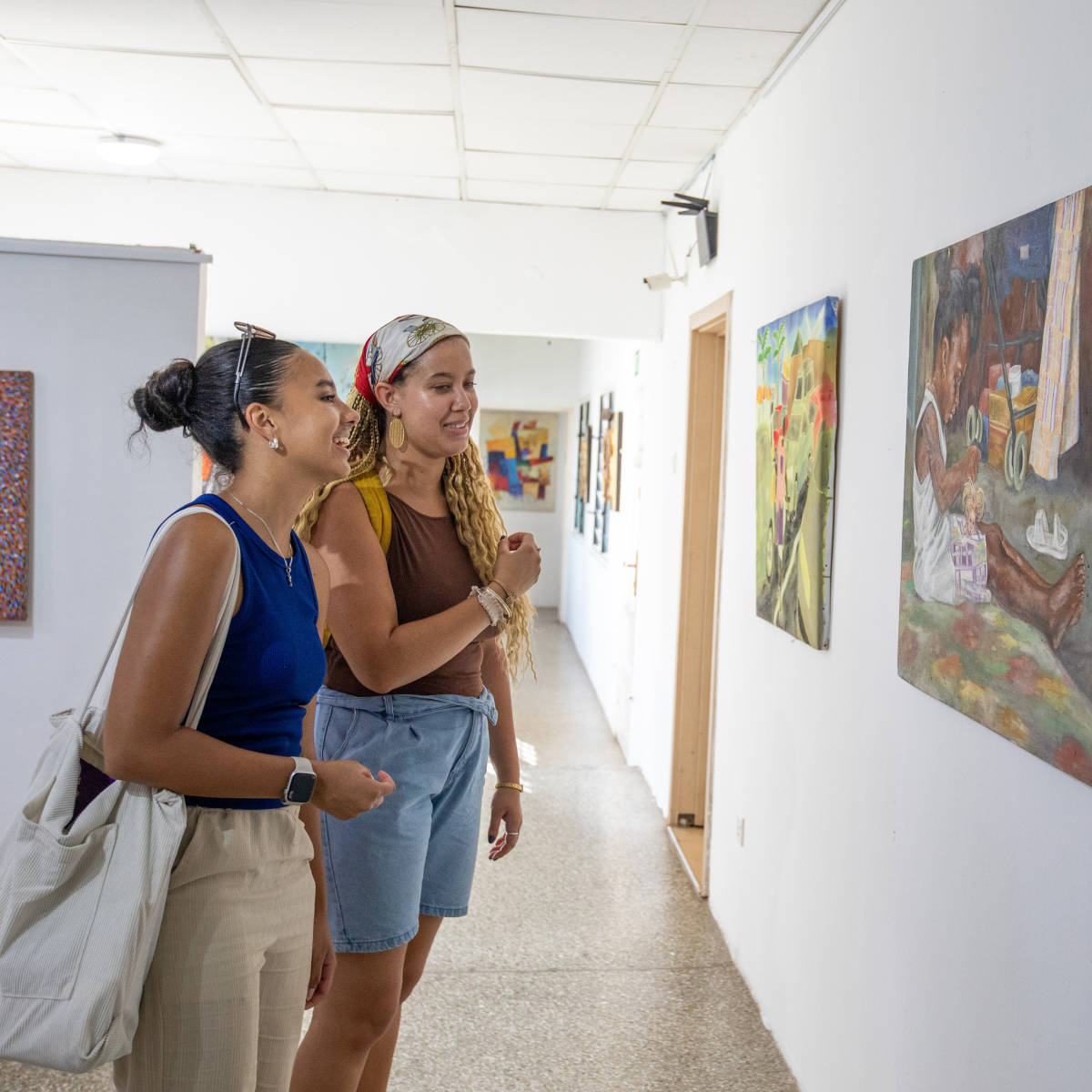 Students smile in front of a painting.