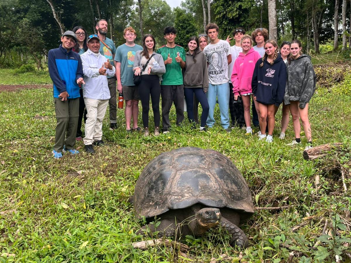 students with a giant tortoise in the Galapagos on a teen travel program