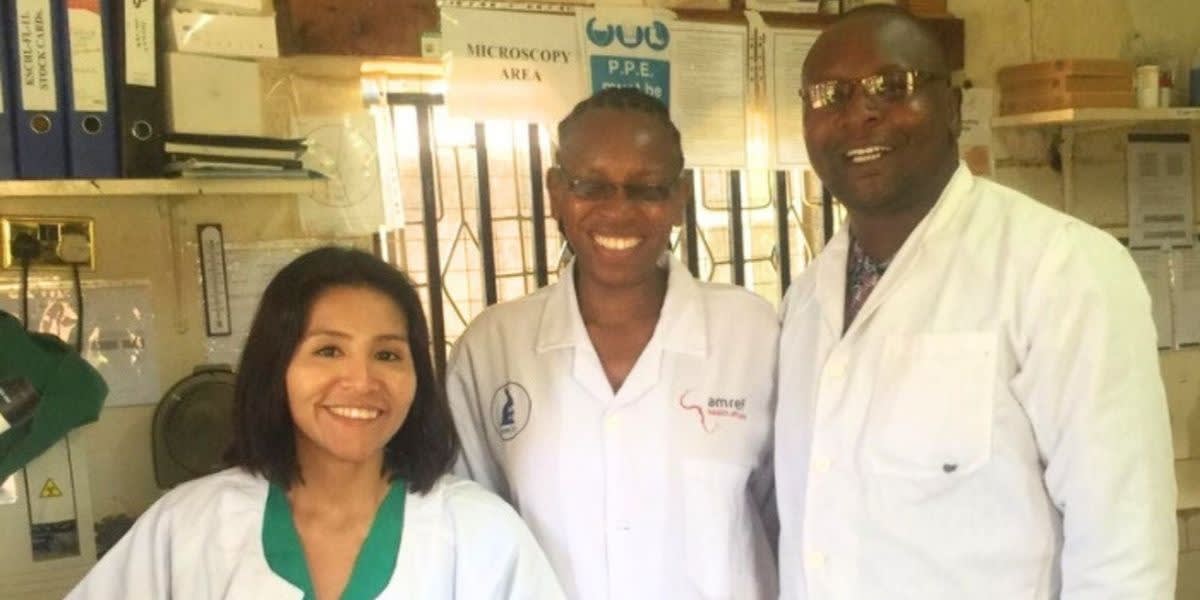 Three smiling people wearing white lab coats.
