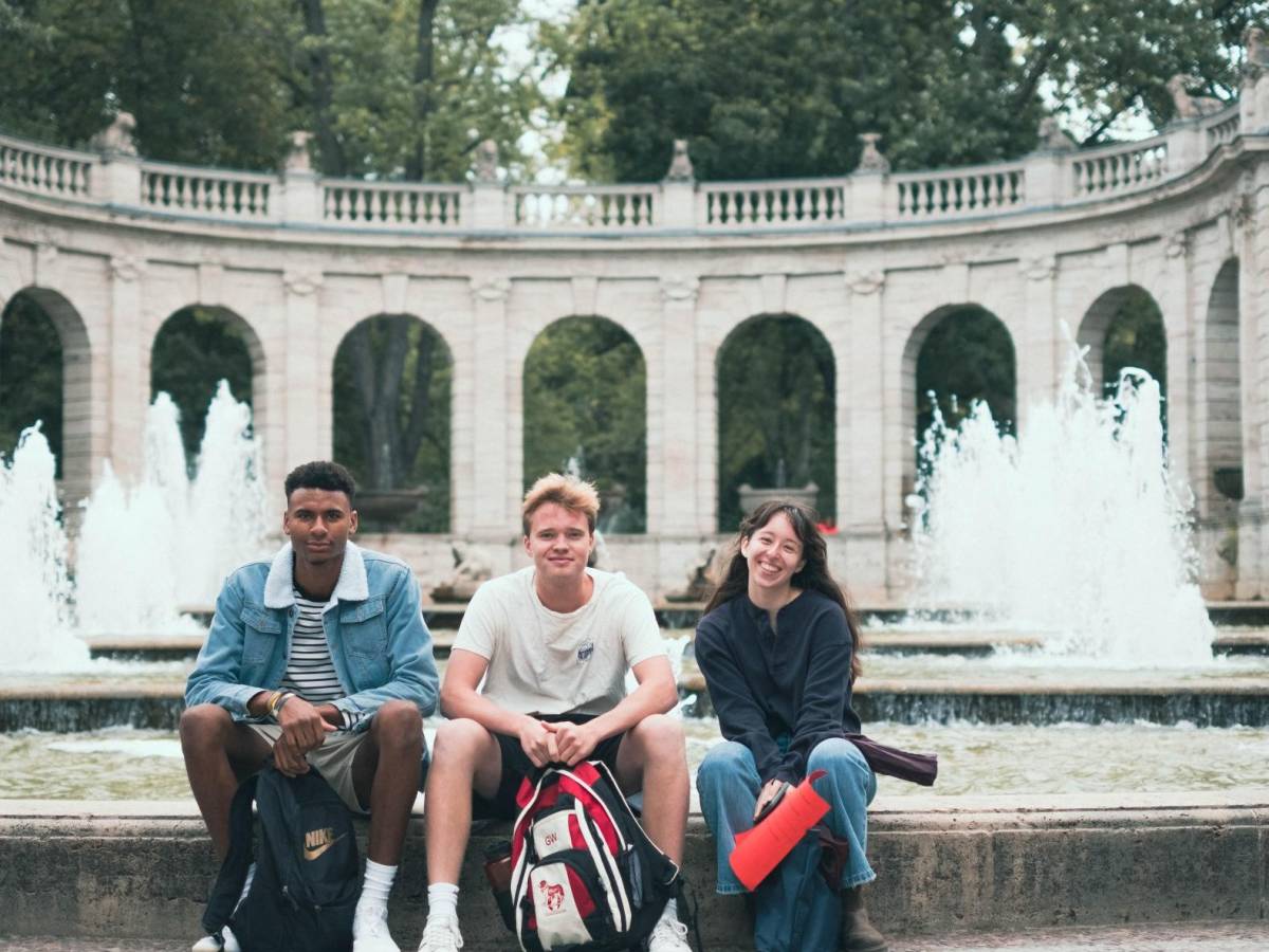 Three students sit by a fountain in Berlin.