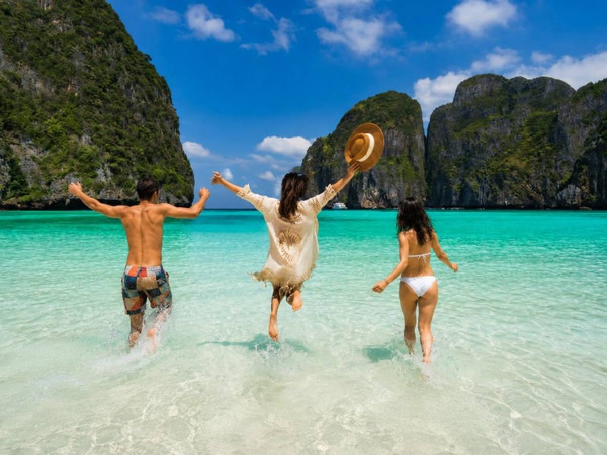 Three travellers running into turquoise water at a Thai beach