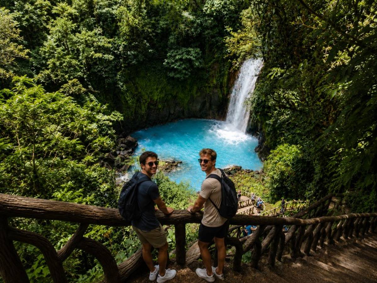 Travellers overlooking a bright blue Costa Rican waterfall