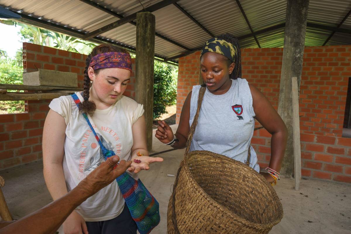 Two girls look at cacao beans in hand.