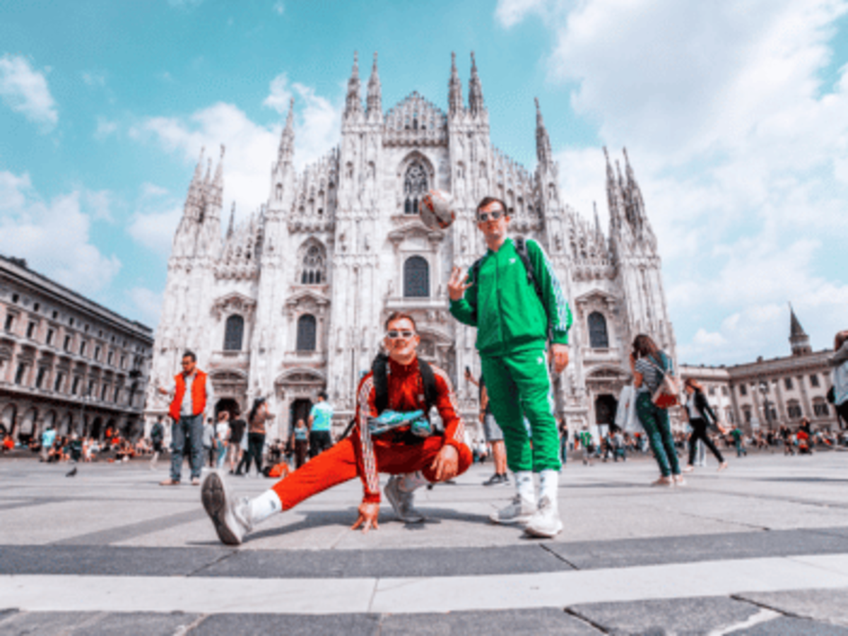 Two men in red and green track suits standing in front of the Duomo in Milan