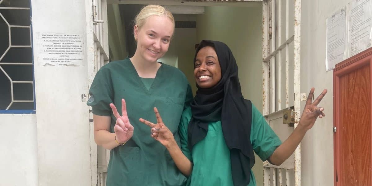 Two smiling women wearing scrubs.