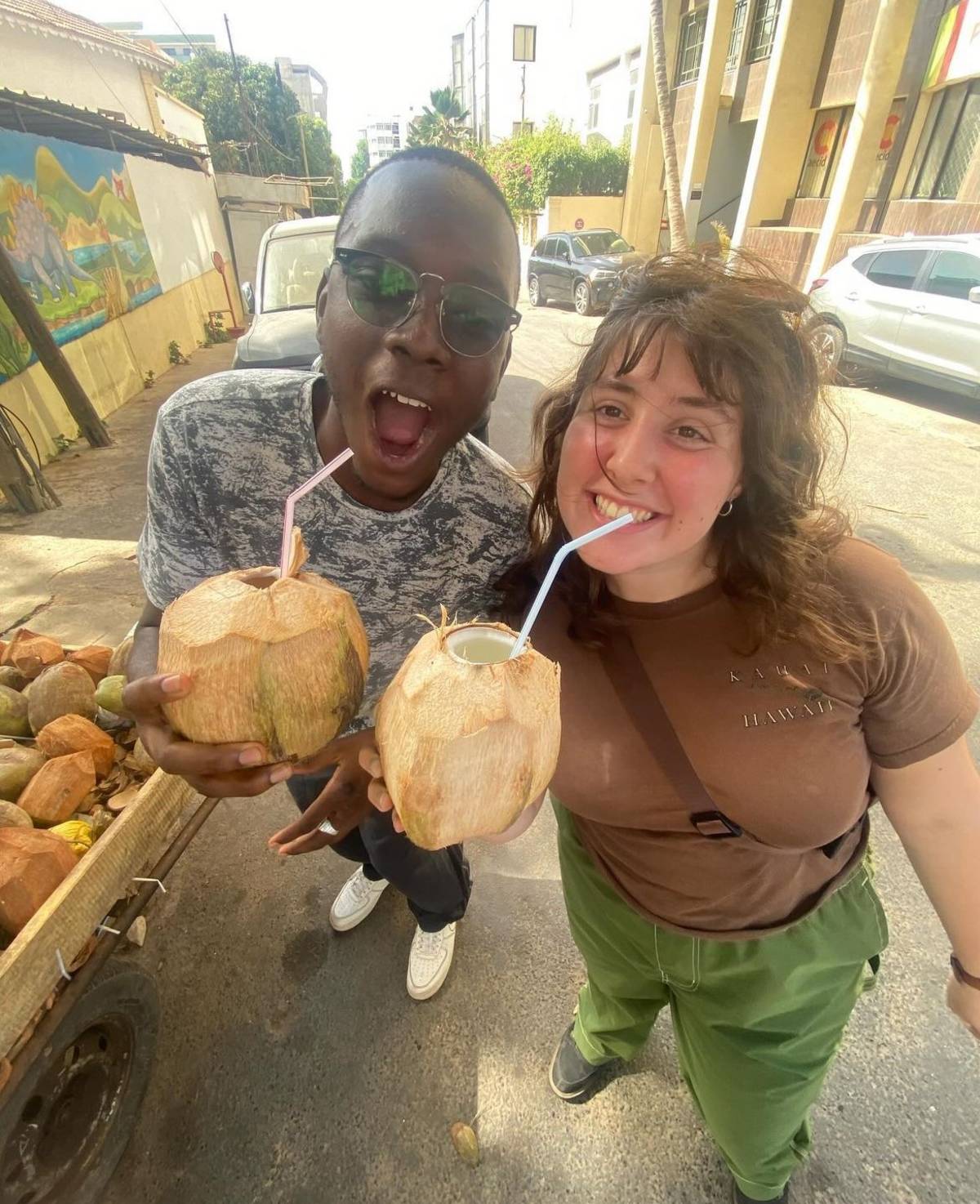 two students drinking from coconuts in a street market in Senegal. 