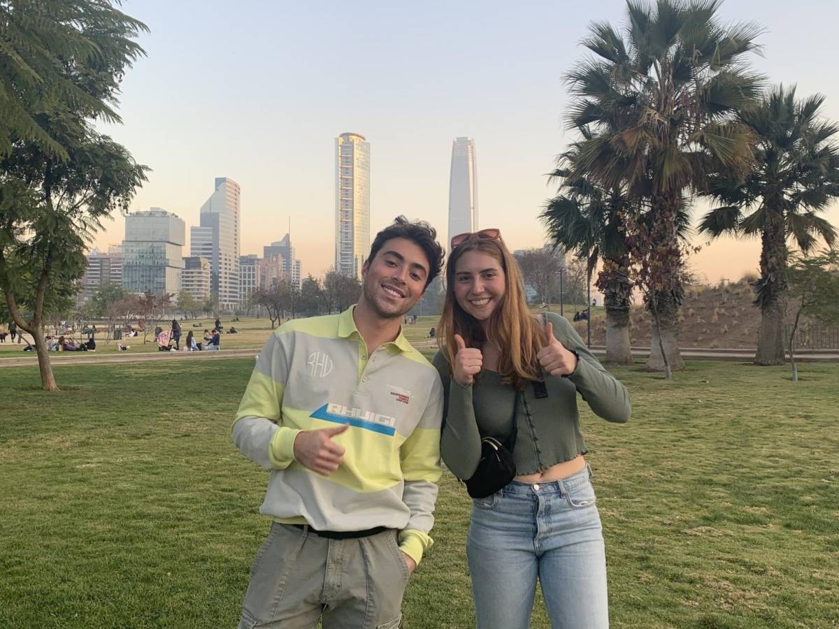 two students in a palm tree-lined park in front of buildings in downtown Santiago