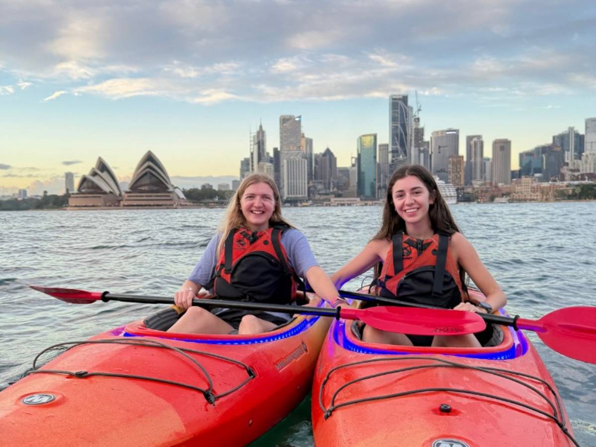 Two women in kayaks in the sea in front of the Sydney Harbour Bridge