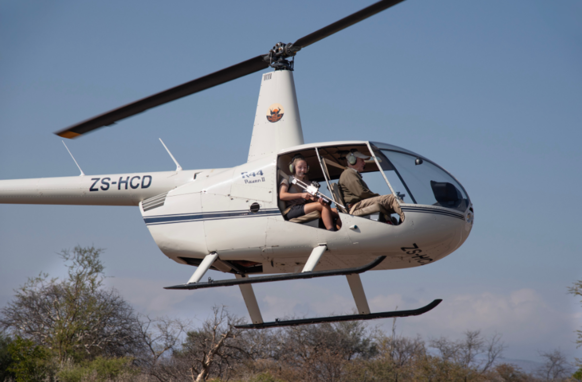 Volunteer in helicopter practising their darting skills as part of the veterinary darting course