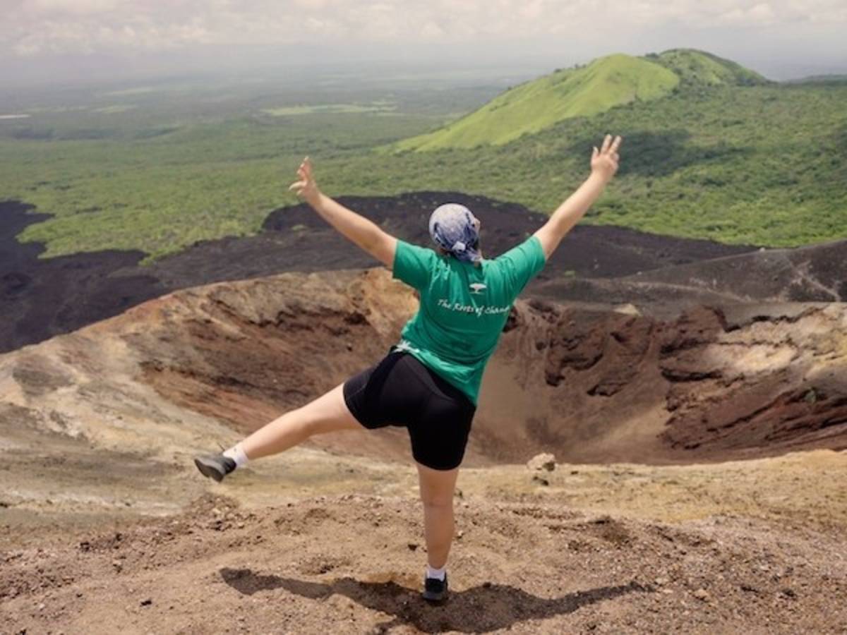 Volunteer posing in front of volcanic crater during volcano adventure